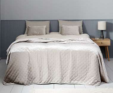 Bézs színű ágytakaró egy ágyon párnákkal egy hálószobában