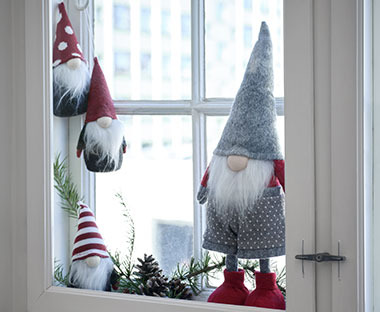 Különböző méretű karácsonyi manók egy ablakpárkányban