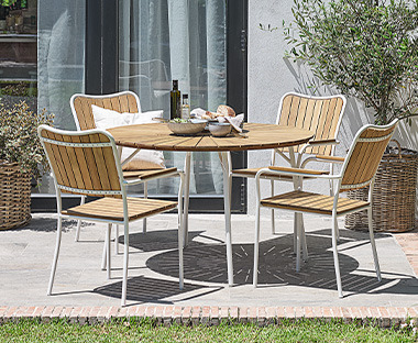 Natúr színű kerek kerti asztal fehér lábakkal és kerti székekkel egy teraszon