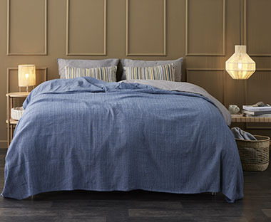 Nagyméretű kék ágytakaró egy ágyon egy hálószobában