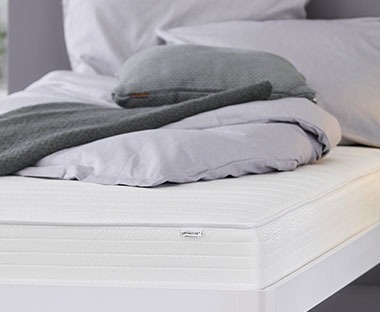 Rugós matrac ágyon szürke ágyneművel