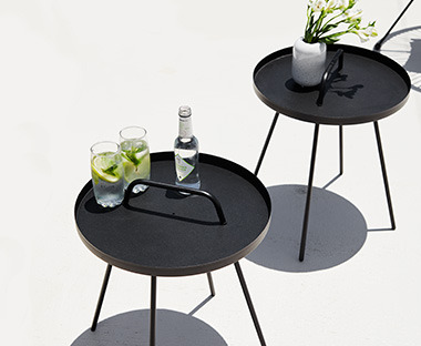 Két fekete kerek kerti kisasztal rajta italokkal