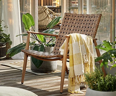 Natúr szék növényekkel és pléddel az ablak előtt