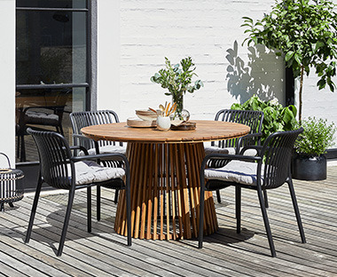 Kerti asztal és fekete kerti székek dekorációkkal egy teraszon