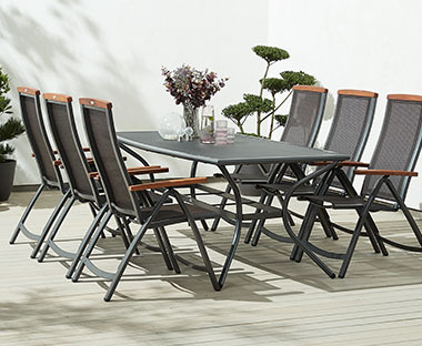 Szürke kerti asztal és szürke állítható kerti székek egy teraszon
