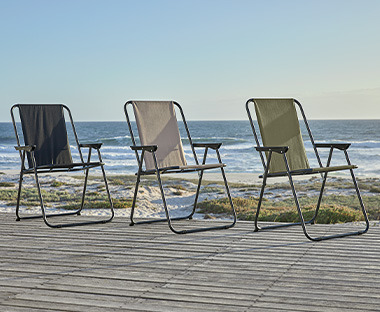 Fekete, zöld és khaki kemping székek egy teraszon a tengerparton