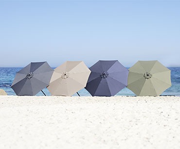 sötétszürke, fekete,bézs és olívazöld napernyők a homokban