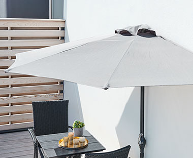 napernyő falra erősítve teraszon kerti asztallal