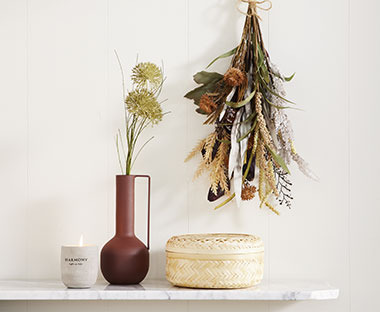 Váza műnövényekkel és gyertyával a polcon natúr, barna színekben