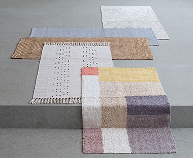 Különböző színű és méretű szőnyegek a padlóra leterítve 
