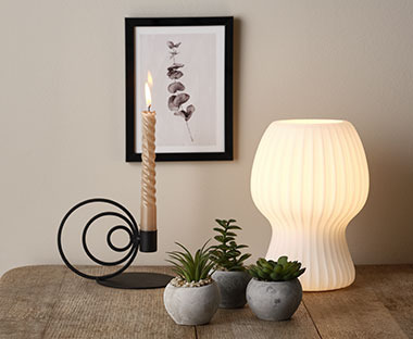 Fehér asztali lámpa dekor termékekkel a polcon