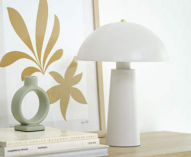 Fehér asztali lámpa mellette gyertyatartóval és képkerettel
