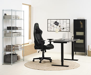 Fekete színű gamer szék, állítható magasságú íróasztal és vitrin egy dolgozószobában