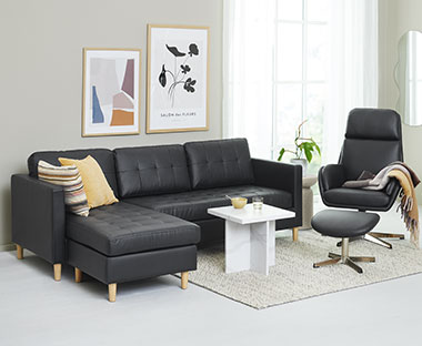 Fekete fotel és kanapé fehér sarokasztallal egy nappaliban