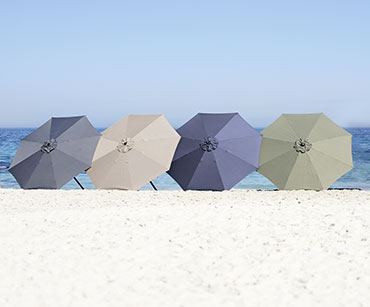 Szürke, bézs, olívazöld és sötétékék napernyők a homokban