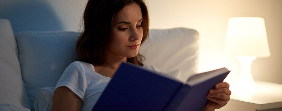 Ágyban olvasó nő