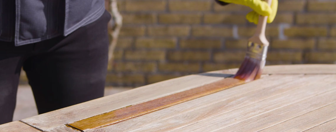 Egy személy bemutatja a fából készült kerti bútorok ápolását