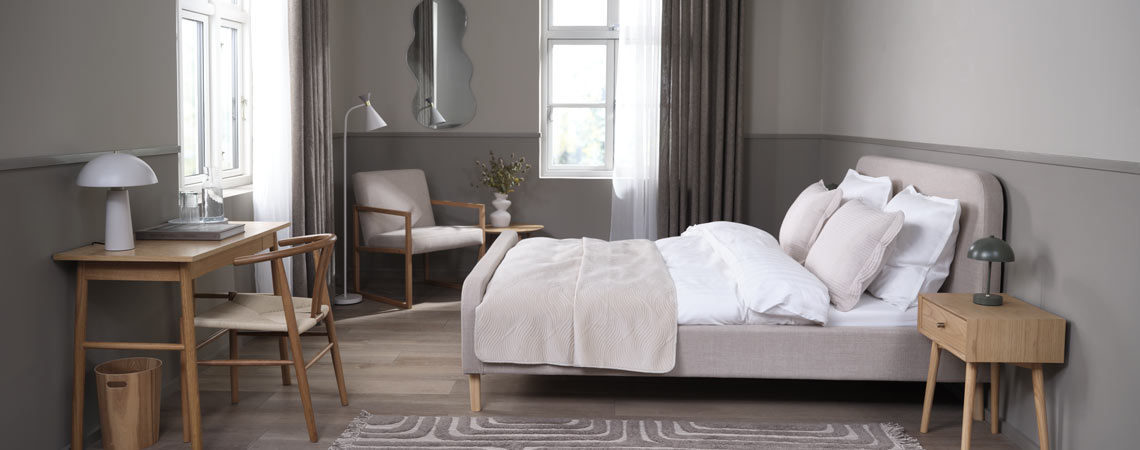 Kárpitozott ágykeret, fotel, írósztal és szék egy hálószobában