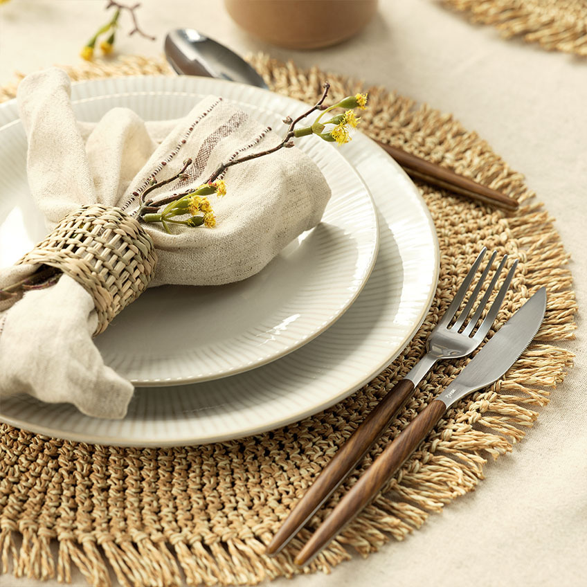 Étkészlet: fehér fodros szélű tányér, textilszalvéta, szalvétagyűrű, evőeszköz készlet és tányéralátét