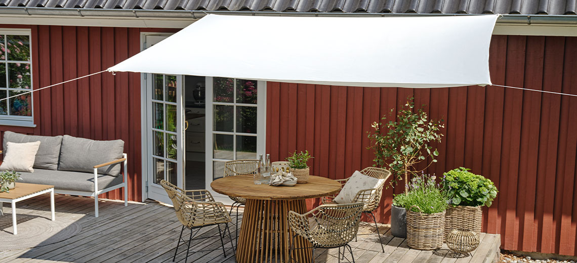 Nagy méretű szögletes fehér napvitorla teraszon lévő kerti étkezőszett felett kifeszítve