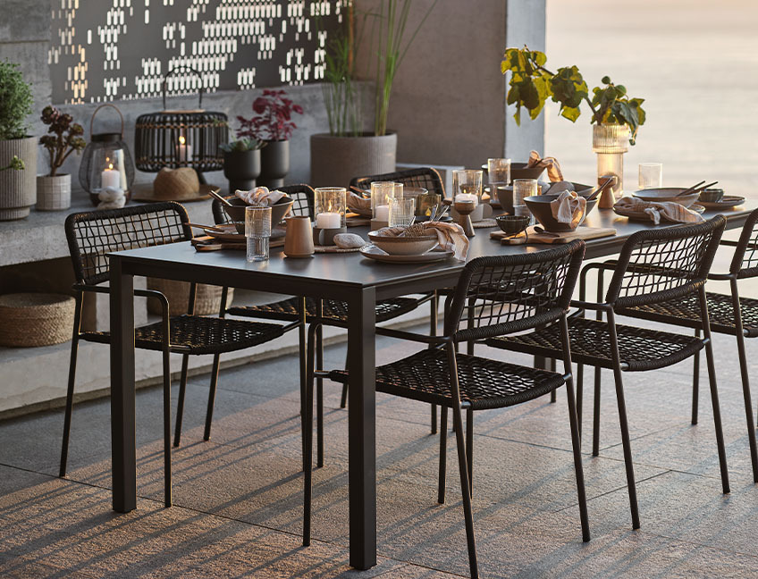 Kerti étkezőasztal és székek étkészlettel egy teraszon a naplementében