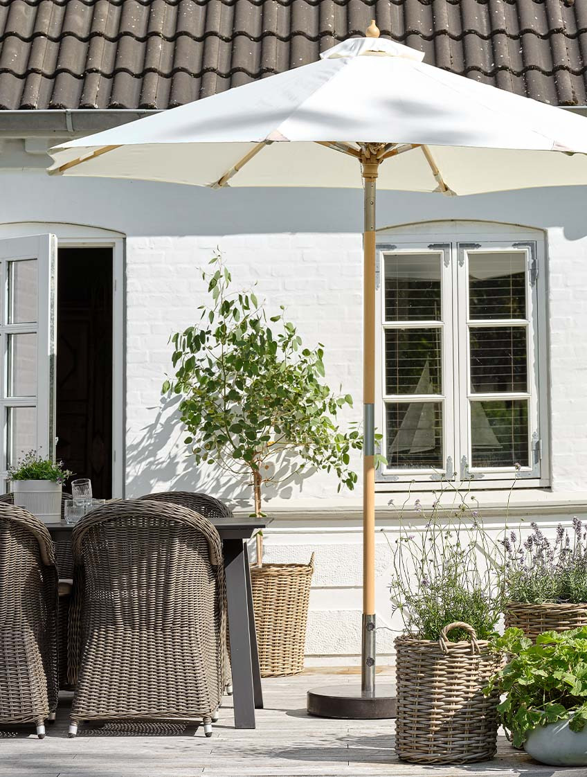 Klasszikus törtfehér napernyő egy teraszon kerti asztallal és kerti székekkel