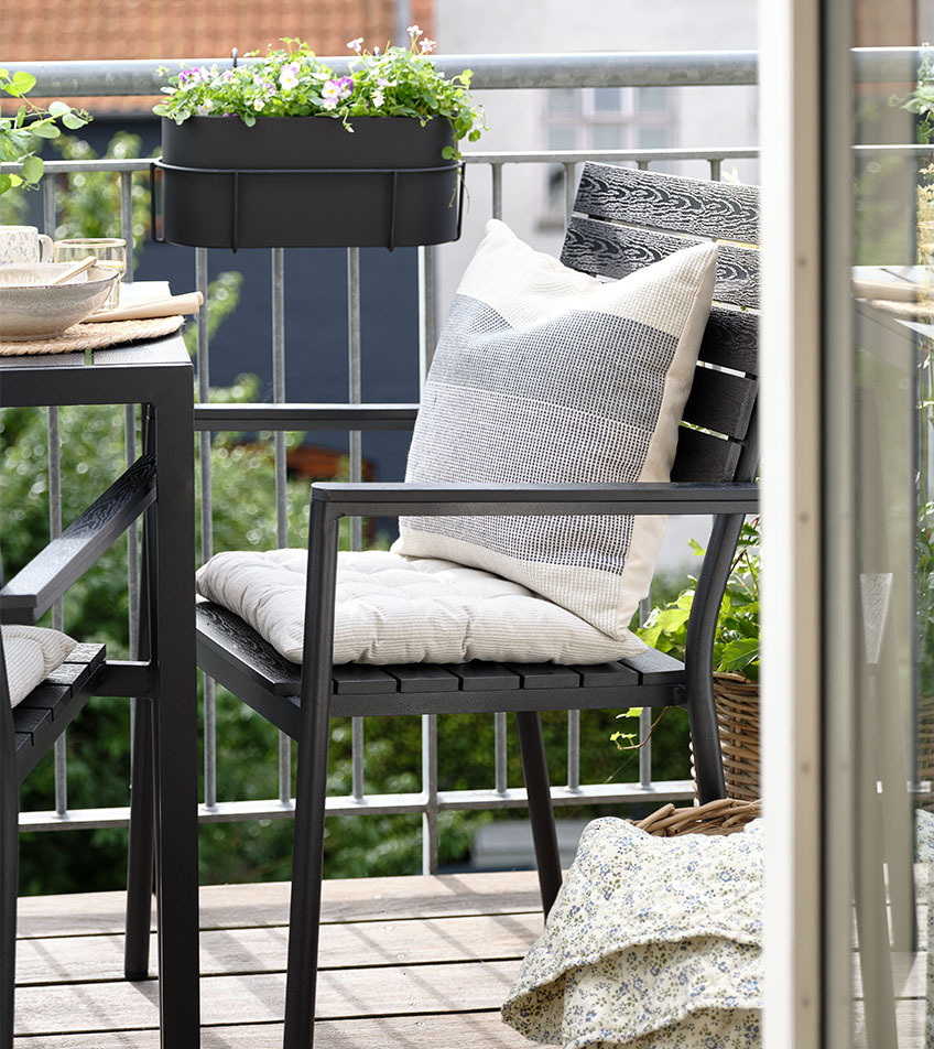 Fekete, rakásolható kerti szék ülő- és hátpárnával egy erkélyen