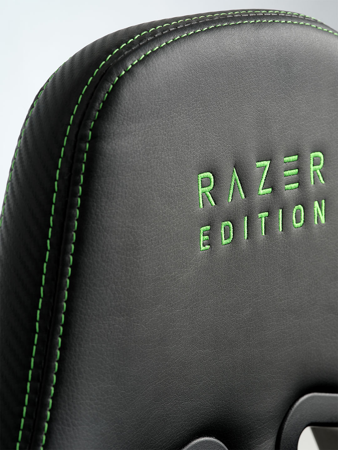 TYPE Z – RAZER EDITION™ BY LEGEND gamer szék Közeli kép egy fekete Razer gamer székről zöld varrással, a háttámláján zölddel hímzett "RAZER EDITION" felirattal.
