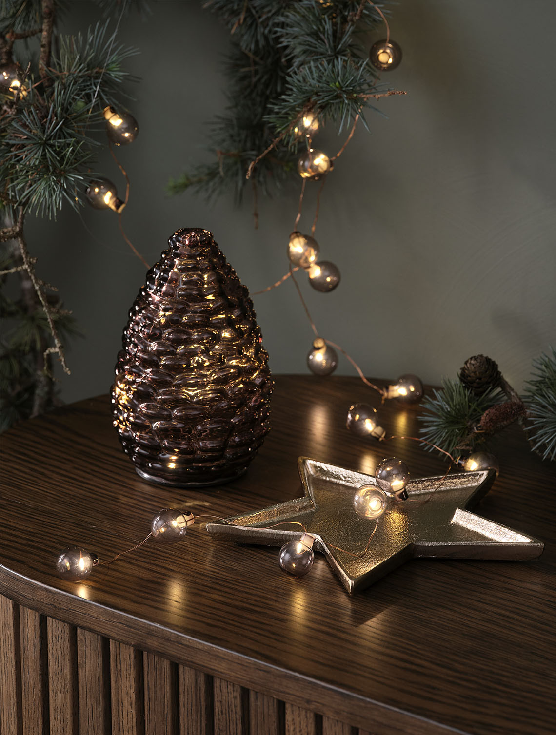 DELLING karácsonyi toboz és ALV fényfüzér Dekoratív karácsonyi fények, például üveg tobozok és arany gömbös fényfüzérek a tálaló tetején