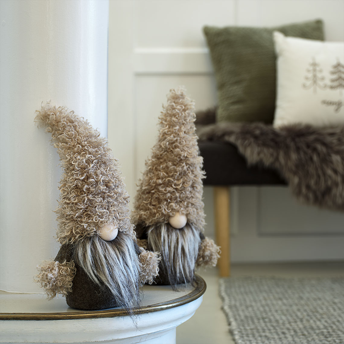 Kisméretű karácsonyi manók zöld és barna árnyalatokban egy tálaló szekrényen