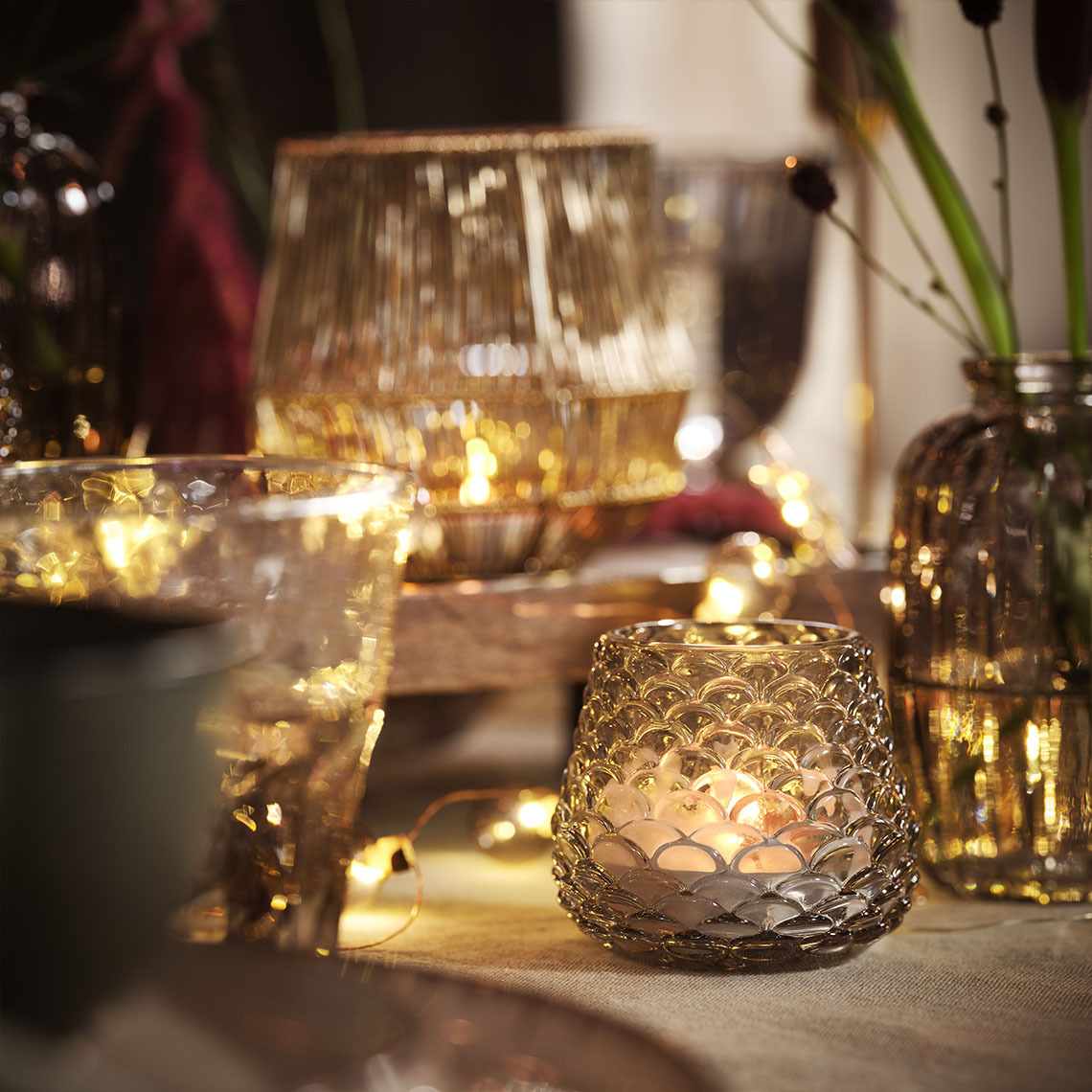 Étkezőasztal gyertyákkal, teamécsesekkel és fényfüzérekkel megvilágítva