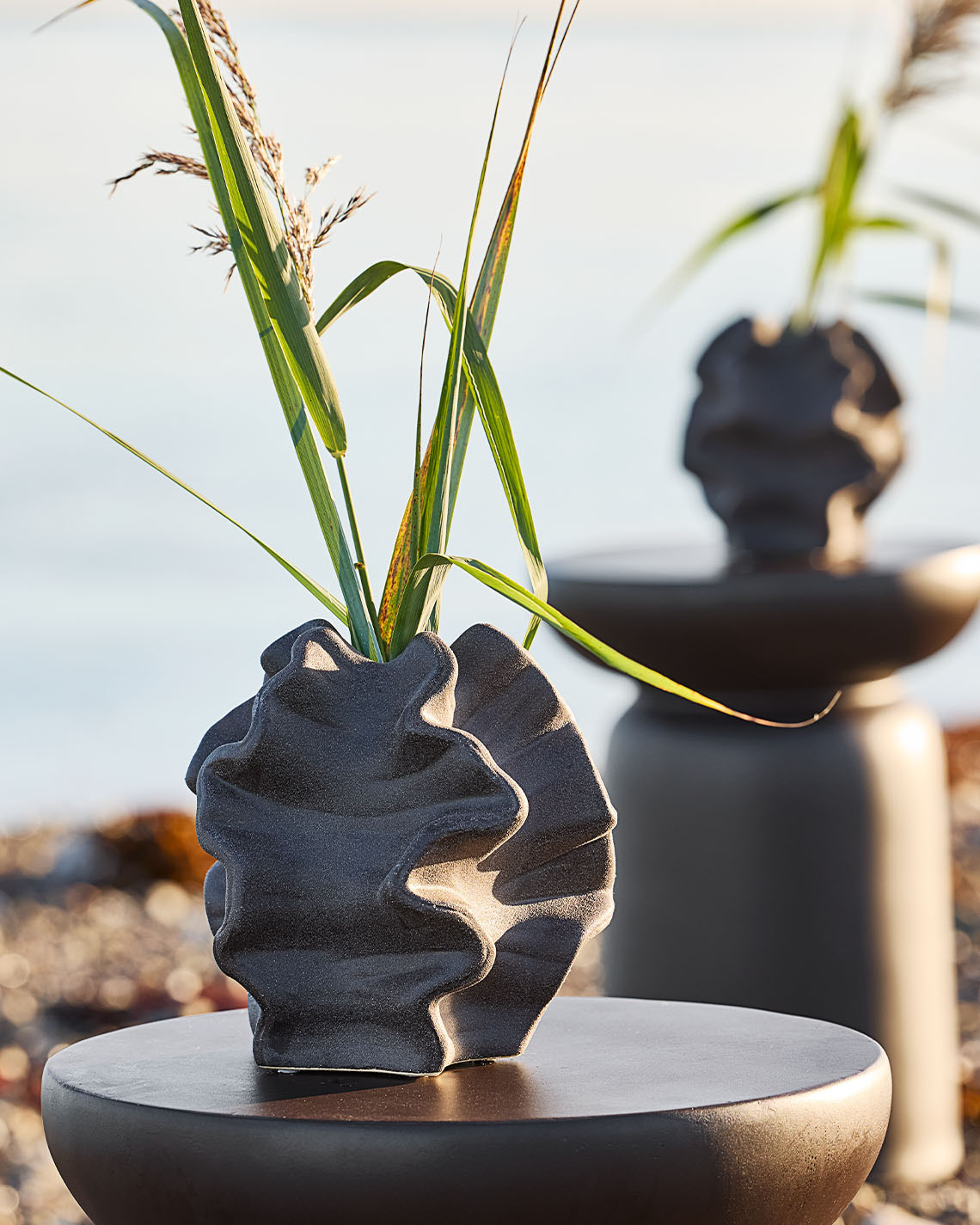 Organikus formájú váza egy állványon a strandon