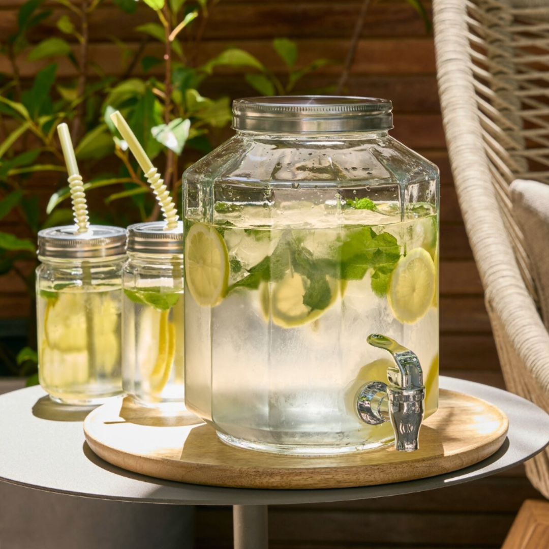 GLASS szívószálas ivópoharak és VANN csapos üveg Csapos üveg poharakkal és limonádéval egy kertben
