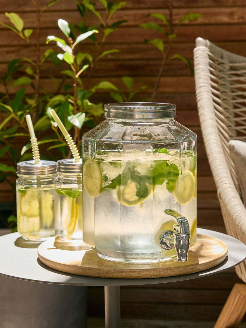 Csapos üveg és szívószálas ivópoharak limonádéval egy asztalon
