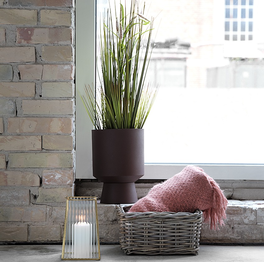 JOHN plant pot with GODSKE artificial plant, TOMMY lantern, and EIDE basket with a LINNEA throw in front of a window Plant pot with artificial plant, lantern, and basket with a pink throw in front of a window