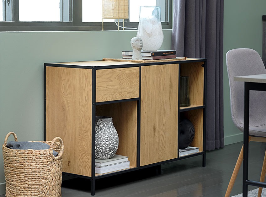 TRAPPEDAL sideboard in oak and black with the MATHIAS vase An oak sideboard beneath a window in a dining room