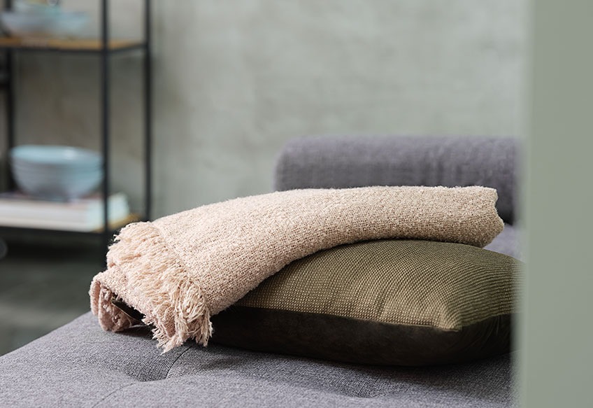 The throw NATTLILJA and the cushion LILJE A throw and a cushion on a sofa