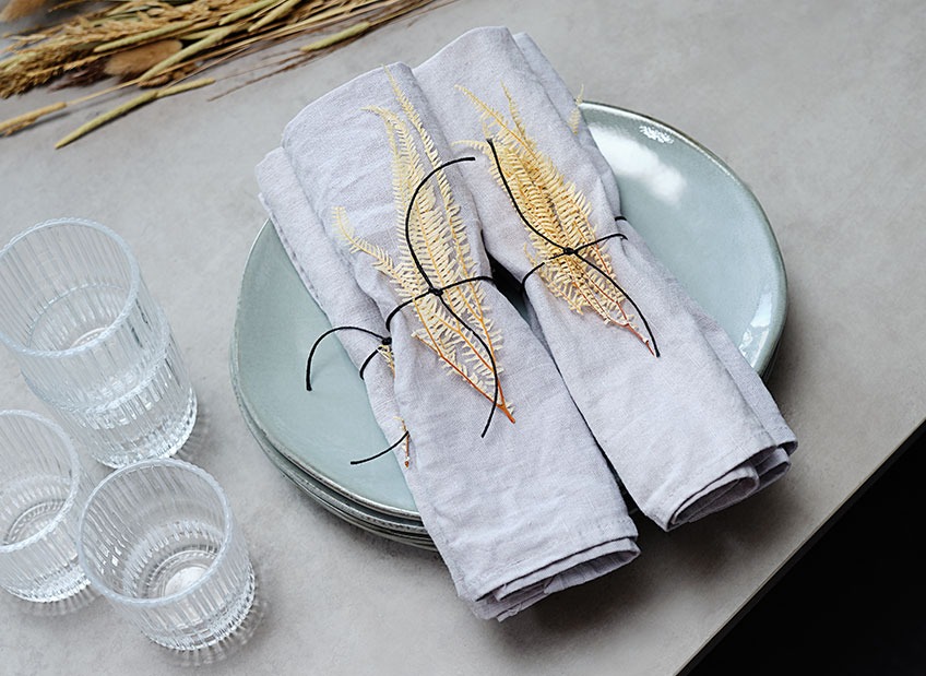 Table set with TONE plates, CLAES glasses and HARSYRA cloth napkins Table set with plate, glasses and cloth napkins decorated with dried leaves and a ribbon