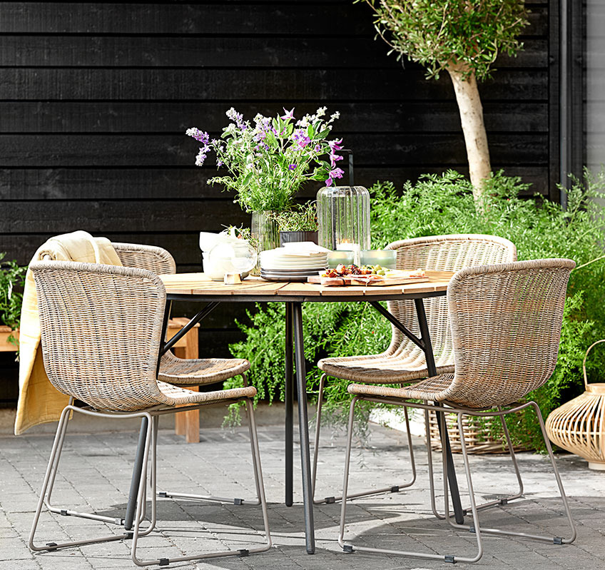 Négy rakásolható szék egy kerek kerti asztal körül egy teraszon
