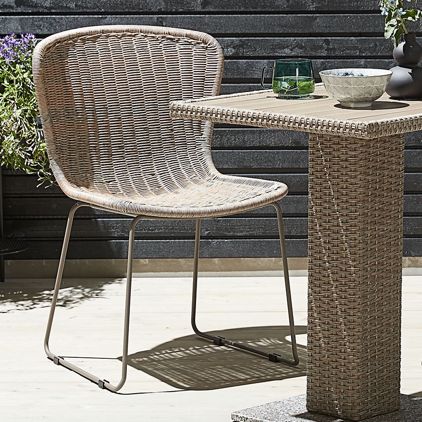 Természetes megjelenésű kerti szék, polyrattanból és acélból egy bisztró asztallal a teraszon 