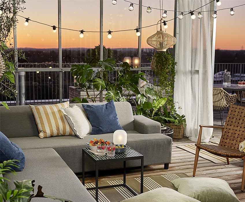 Outdoor setting with string lights, lounge set, cushions, and lanterns