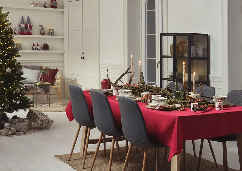 Étkezőasztal karácsonyi hangulatban feldíszítve és karácsonyfa ajándékokkal 