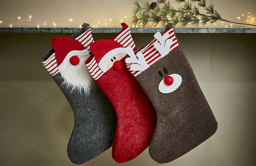 Karácsonyi zoknik lógnak a polcról, mikulás, manó és rénszarvas motívumokkal 