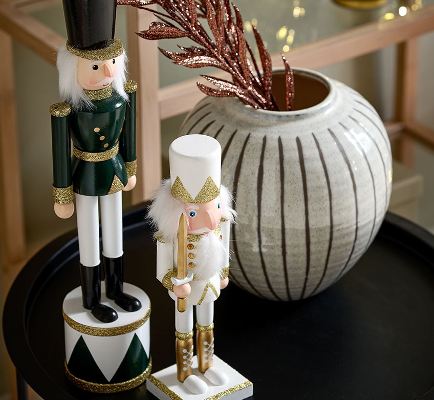 Kettő karácsonyi figura és egy váza a fekete sarokasztalon 