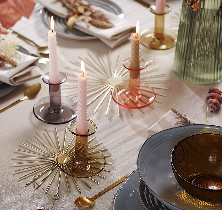 Arany színű dekoráció, üveg gyertyatartók és gyertyák egy Újévi ünnepséghez megterített asztalon