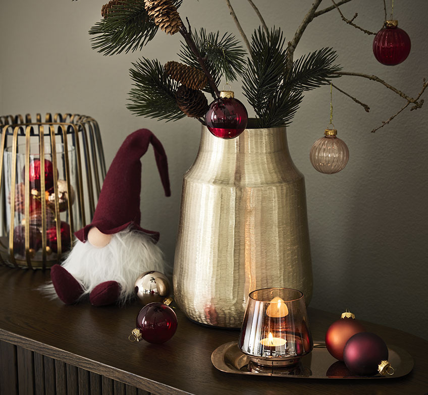 Arany gyertyatartó, karácsonyi manók és arany váza lucfenyő ágakkal és karácsony gömbdíszekkel