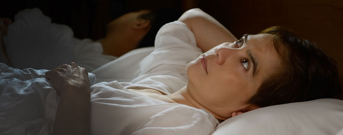 Egy nő álmatlanul fekszik az ágyban 